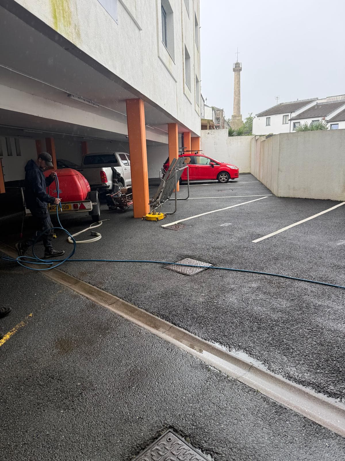 Moore & Franks operative pressure washing a commercial car park beneath an office building, Devon — Cullompton