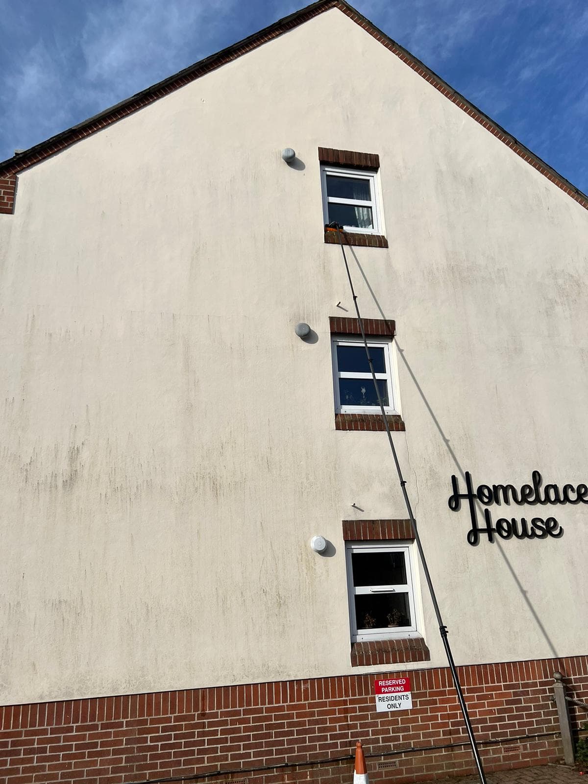 Soft-washing the rendered gable of a block of flats with a telescopic pole, Devon — Crediton