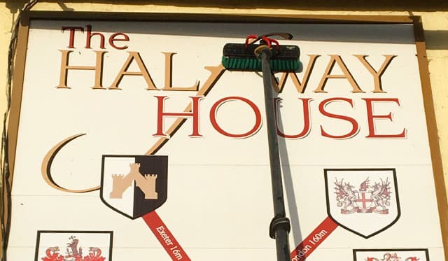 Water-fed pole brush cleaning a painted pub sign, Devon — Cullompton