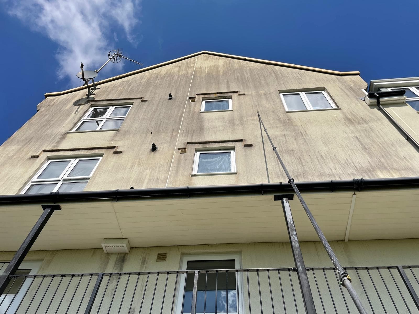 Pole-fed soft washing of an algae-stained rendered apartment gable, three storeys up — Brixham