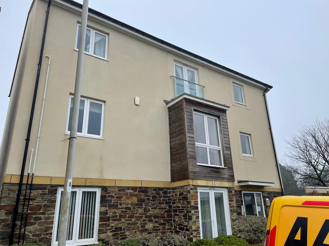 Rendered three-storey apartment block with rows of white uPVC windows, Devon — Moore & Franks window cleaning — Cullompton